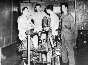Standing over an intricate Armament Dept. mock-up, Gen. Bres of the ROTC and Lt. Col. Messerschmitt talk with Chinese officer.  [Wings]